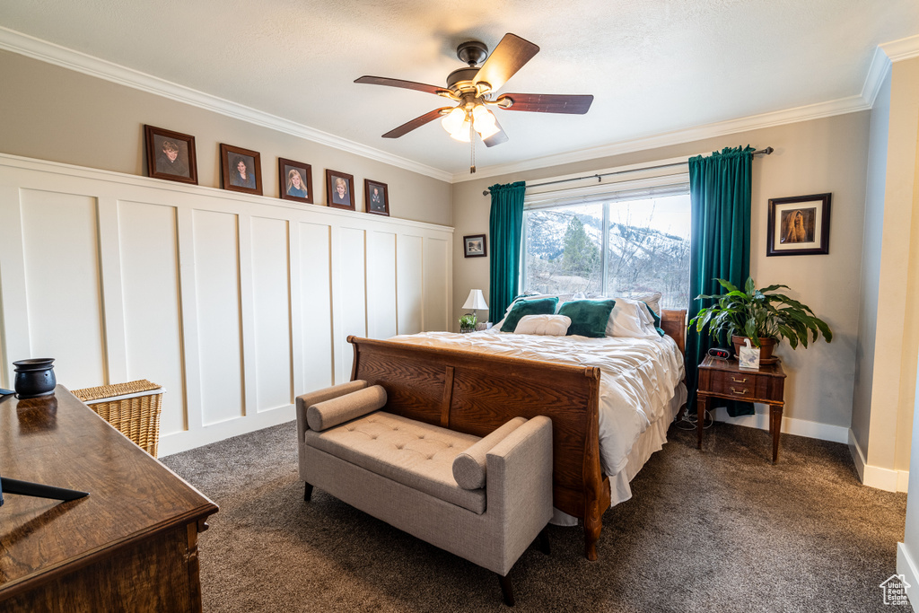 Bedroom featuring dark colored carpet, ornamental molding, and ceiling fan