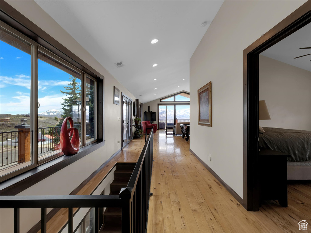Hallway featuring plenty of natural light, light hardwood / wood-style flooring, and lofted ceiling