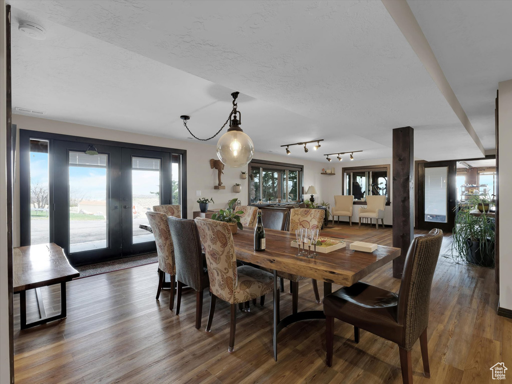 Dining room with french doors, dark hardwood / wood-style flooring, and track lighting