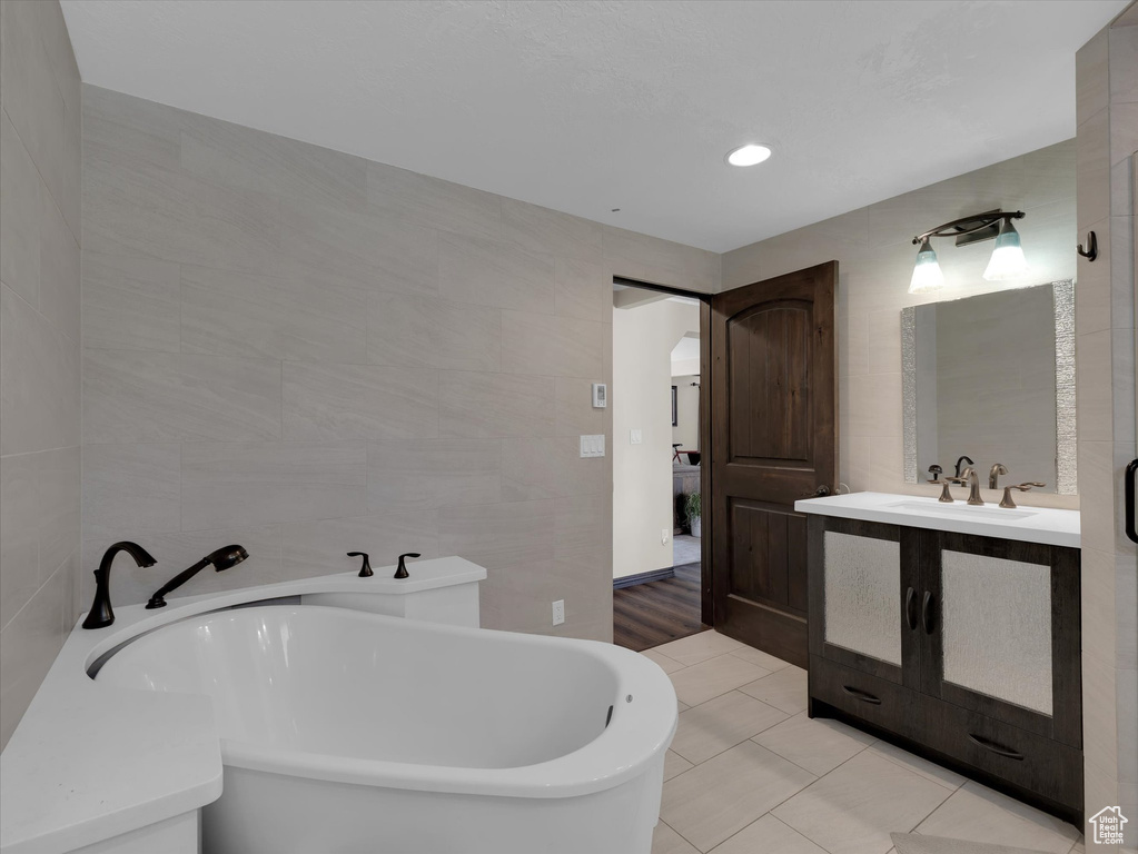 Bathroom featuring tile walls, a bathtub, tile flooring, and vanity