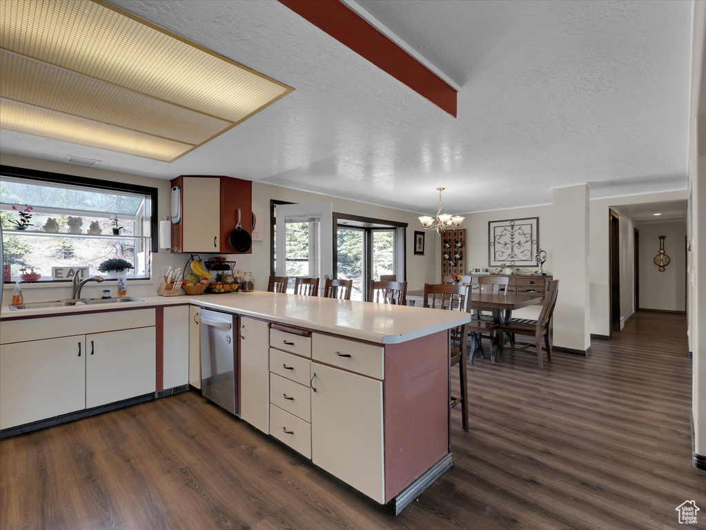 Kitchen featuring dark hardwood / wood-style floors, kitchen peninsula, sink, a notable chandelier, and dishwasher