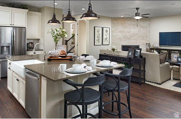 Kitchen featuring appliances with stainless steel finishes, dark hardwood / wood-style flooring, a large fireplace, and pendant lighting