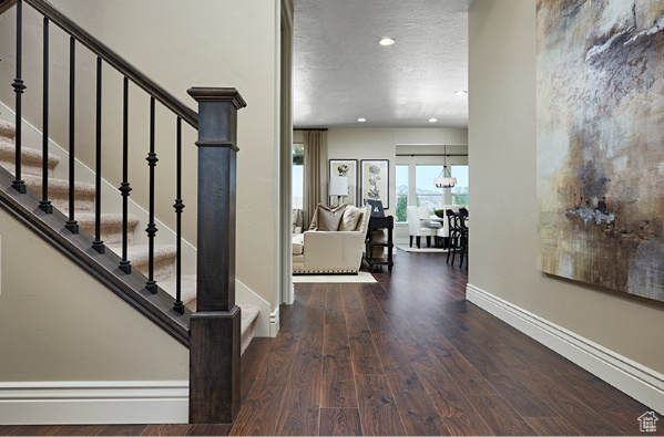 Foyer entrance with dark hardwood / wood-style flooring and a textured ceiling