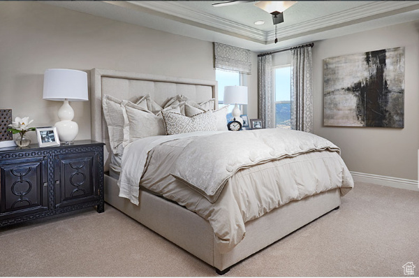 Carpeted bedroom featuring ornamental molding, a tray ceiling, and ceiling fan