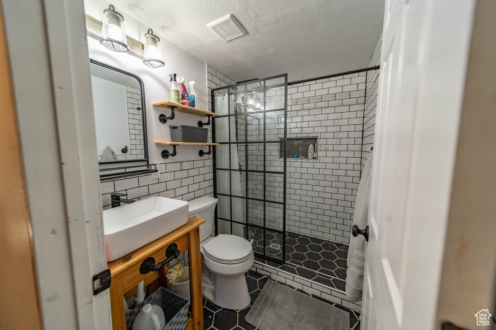 Bathroom with vanity, a textured ceiling, toilet, tile floors, and curtained shower