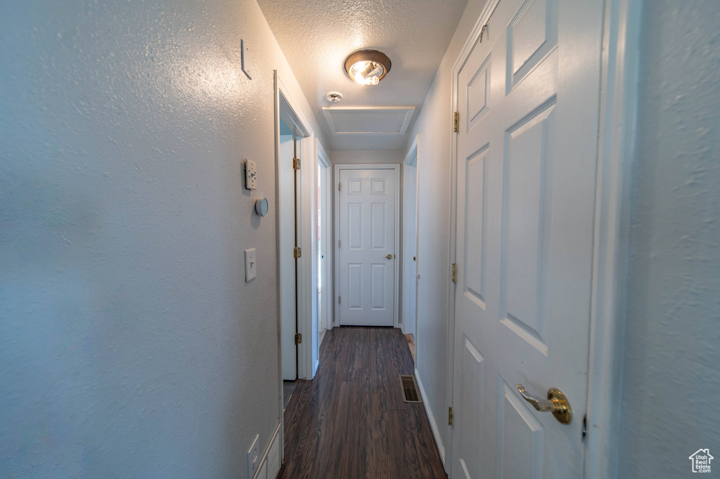 Corridor featuring dark hardwood / wood-style floors and a textured ceiling