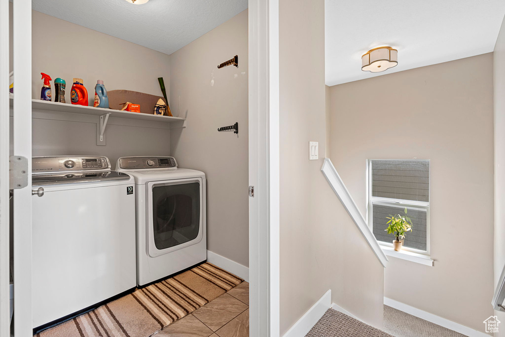 Clothes washing area featuring light tile floors and washing machine and dryer