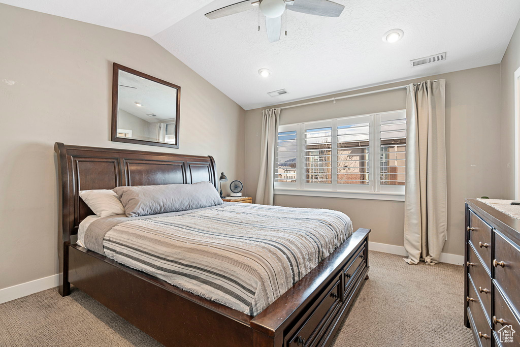 Carpeted bedroom featuring vaulted ceiling and ceiling fan