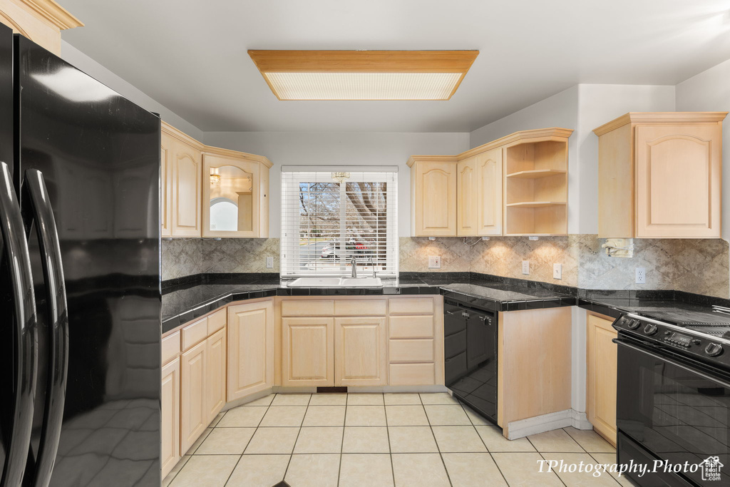 Kitchen with sink, tasteful backsplash, light tile floors, light brown cabinets, and black appliances