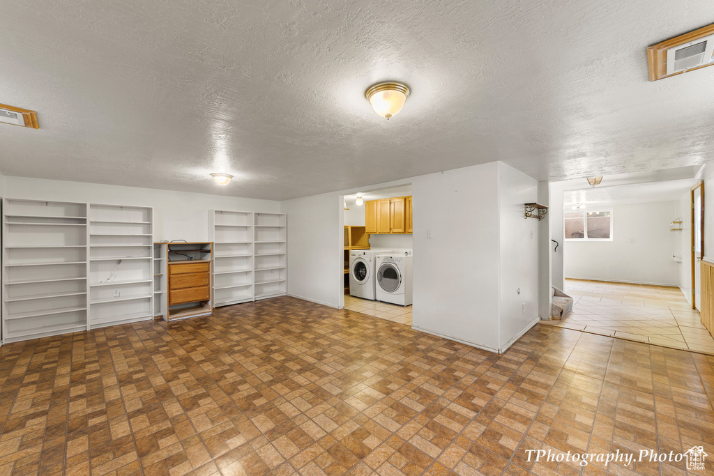 Unfurnished living room with light tile flooring, washer and clothes dryer, and a textured ceiling