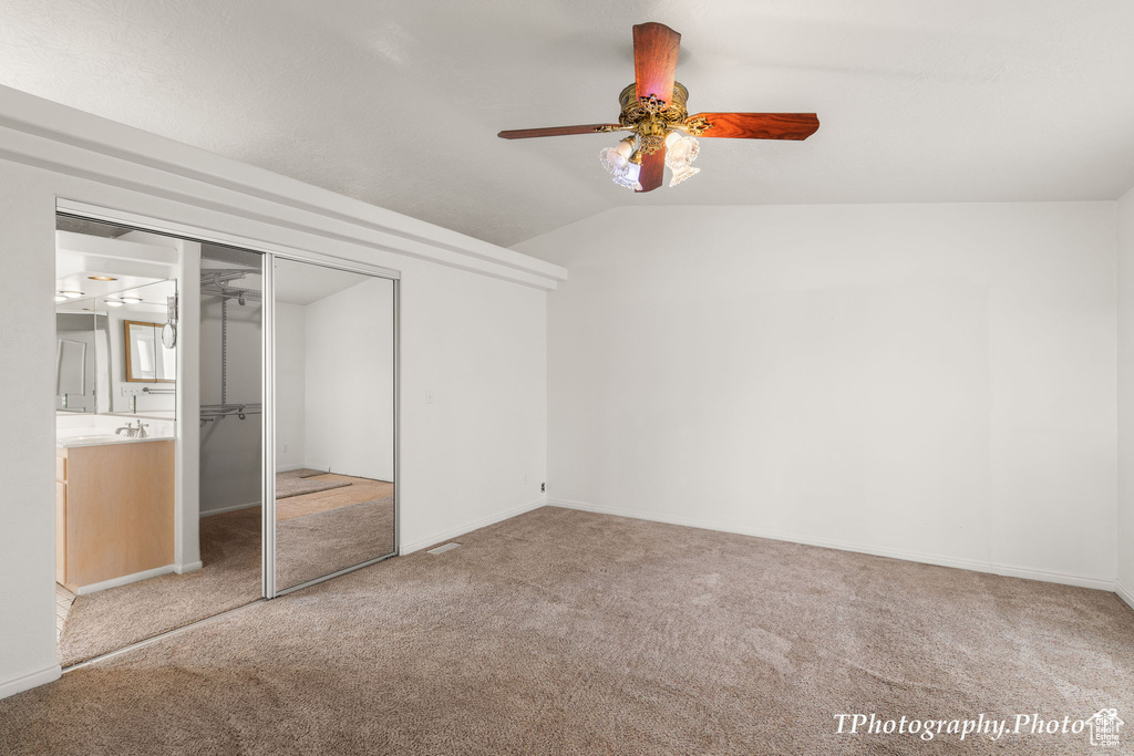 Unfurnished bedroom with light carpet, vaulted ceiling, ceiling fan, and a closet