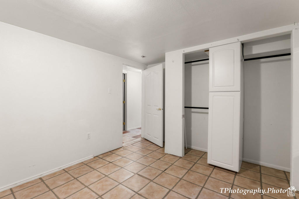 Unfurnished bedroom with light tile floors and a closet