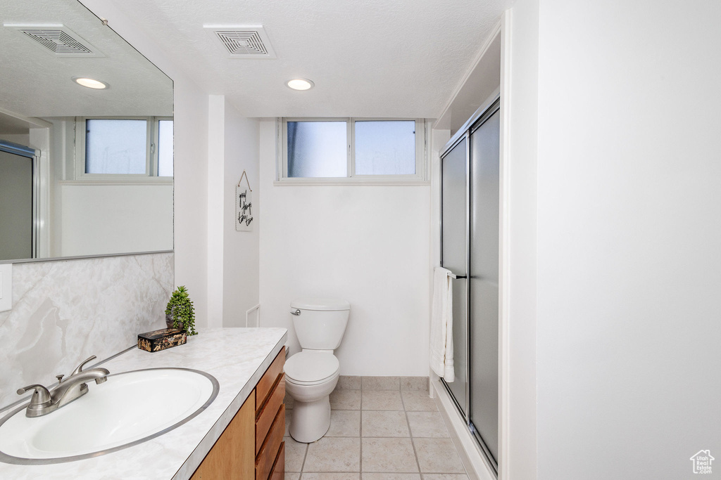 Bathroom with tile floors, a wealth of natural light, toilet, and large vanity