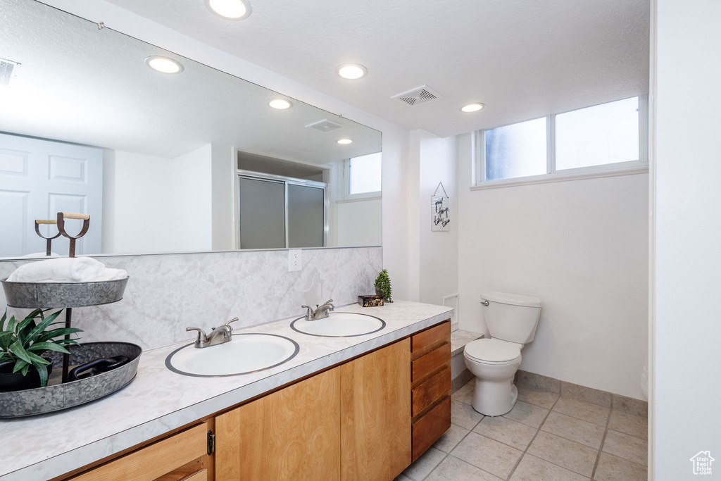 Bathroom with tile flooring, tasteful backsplash, double vanity, and toilet