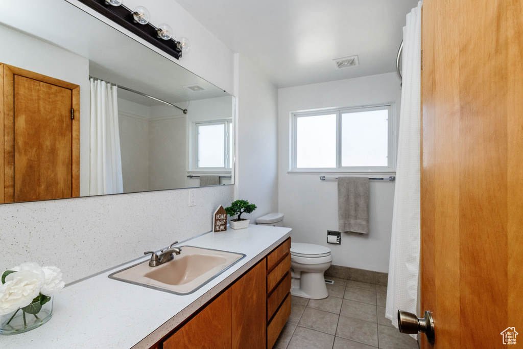 Bathroom with oversized vanity, backsplash, tile floors, and toilet
