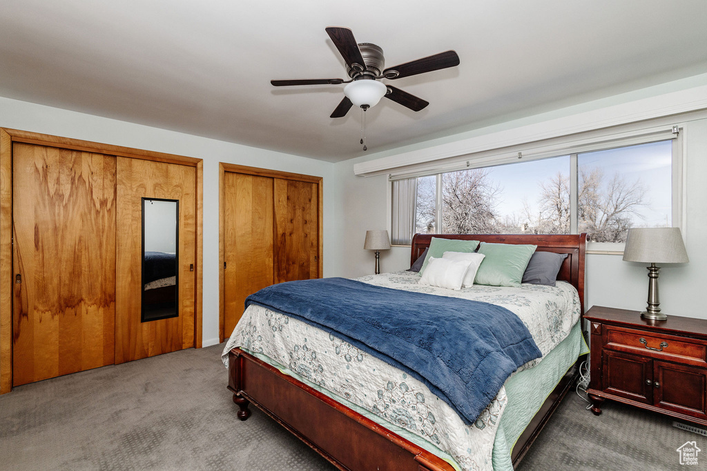 Bedroom featuring multiple closets, light carpet, and ceiling fan