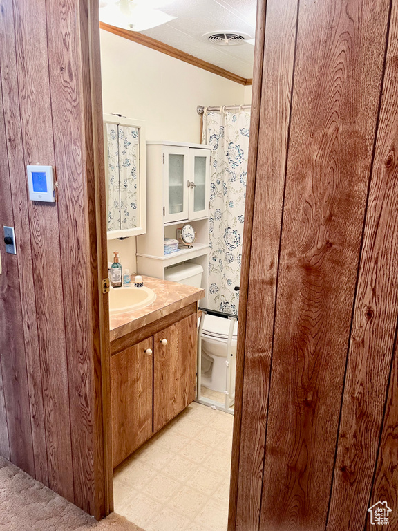 Bathroom with ornamental molding, toilet, tile flooring, and large vanity