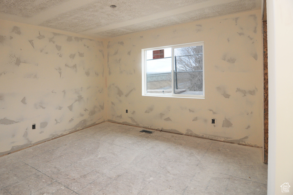 Tiled empty room featuring a textured ceiling