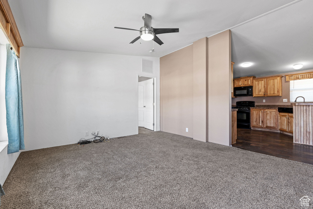 Unfurnished living room featuring dark carpet and ceiling fan