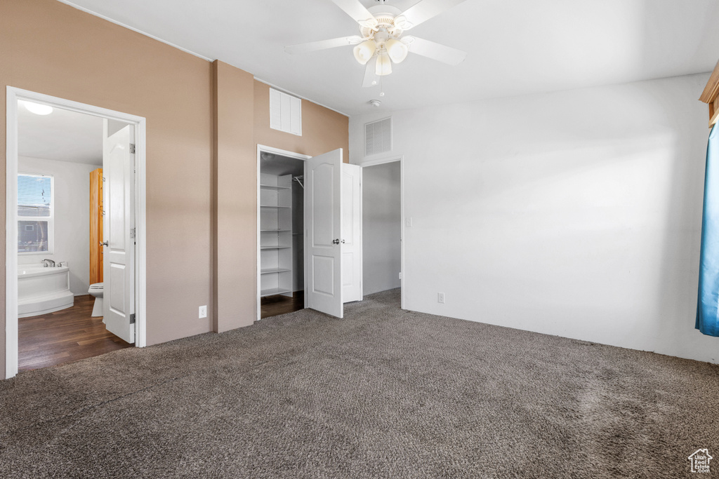 Unfurnished bedroom featuring ceiling fan, a closet, ensuite bath, and dark carpet