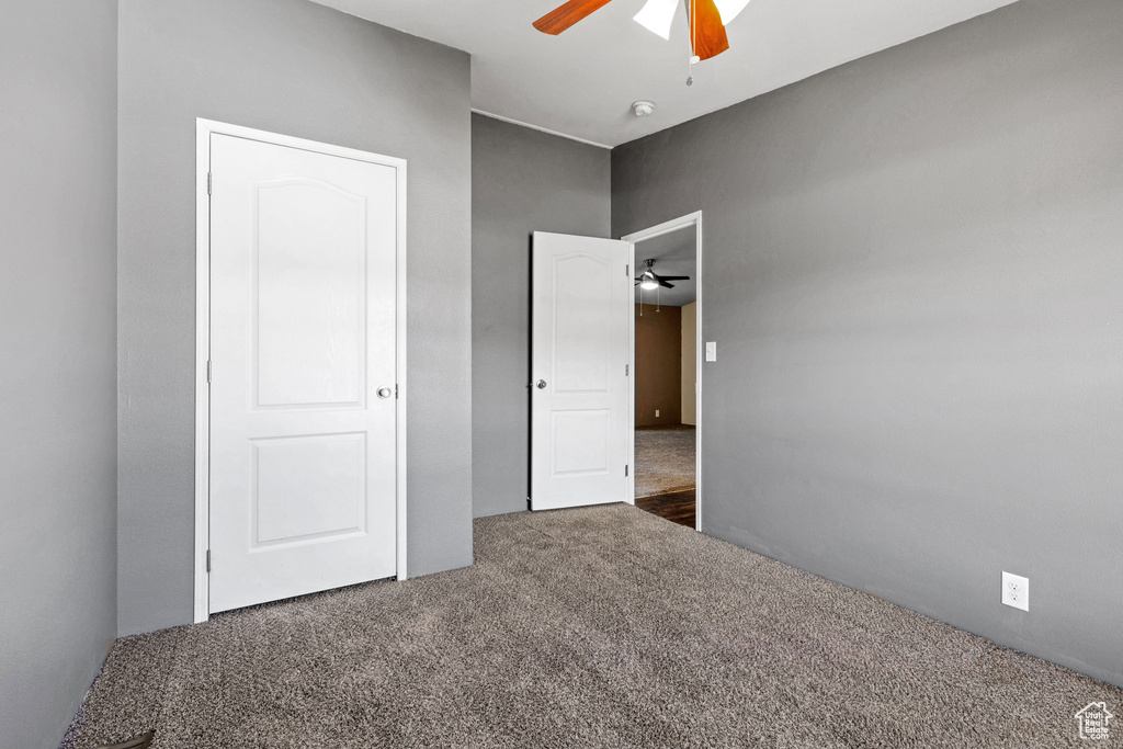 Unfurnished bedroom with ceiling fan and dark carpet