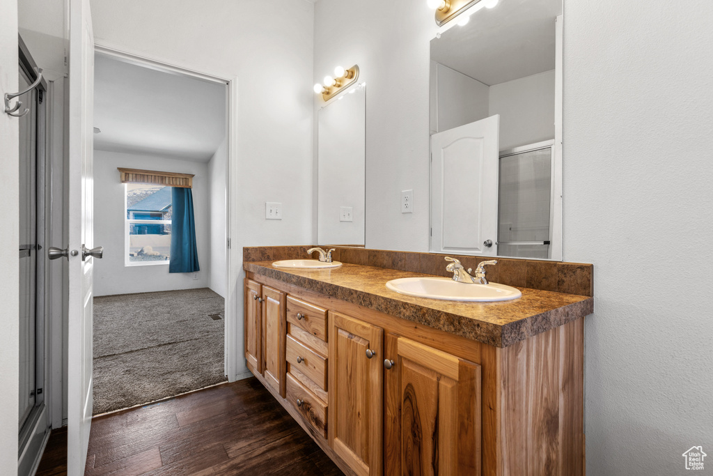 Bathroom featuring vanity with extensive cabinet space, hardwood / wood-style floors, and dual sinks