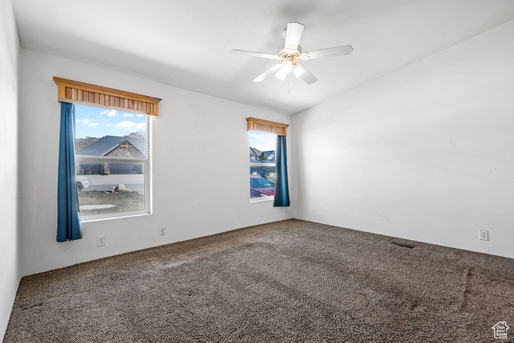 Spare room featuring a healthy amount of sunlight, carpet, and ceiling fan