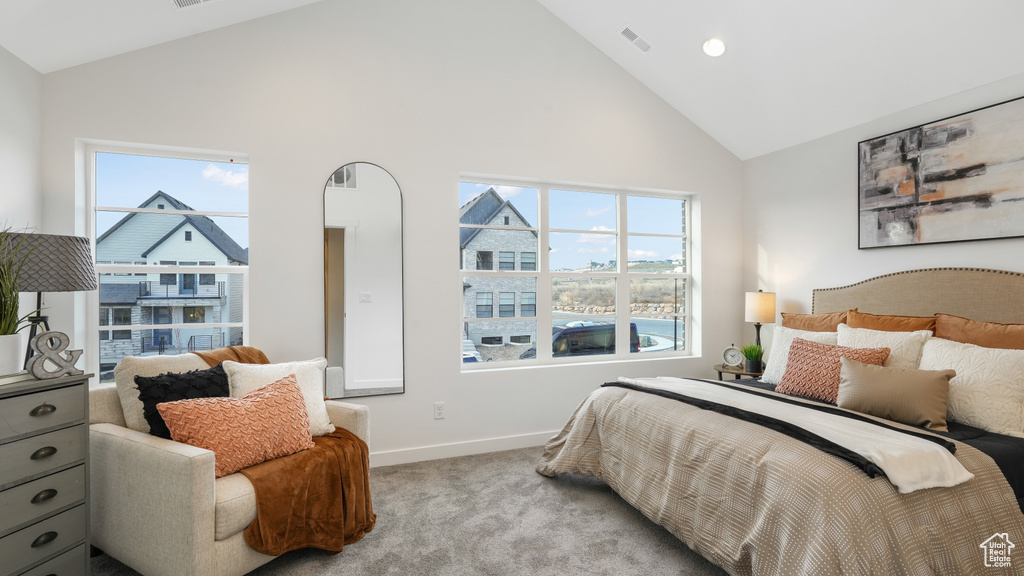 Bedroom featuring light carpet and high vaulted ceiling