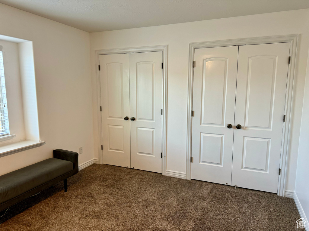 Unfurnished bedroom featuring multiple closets and dark carpet