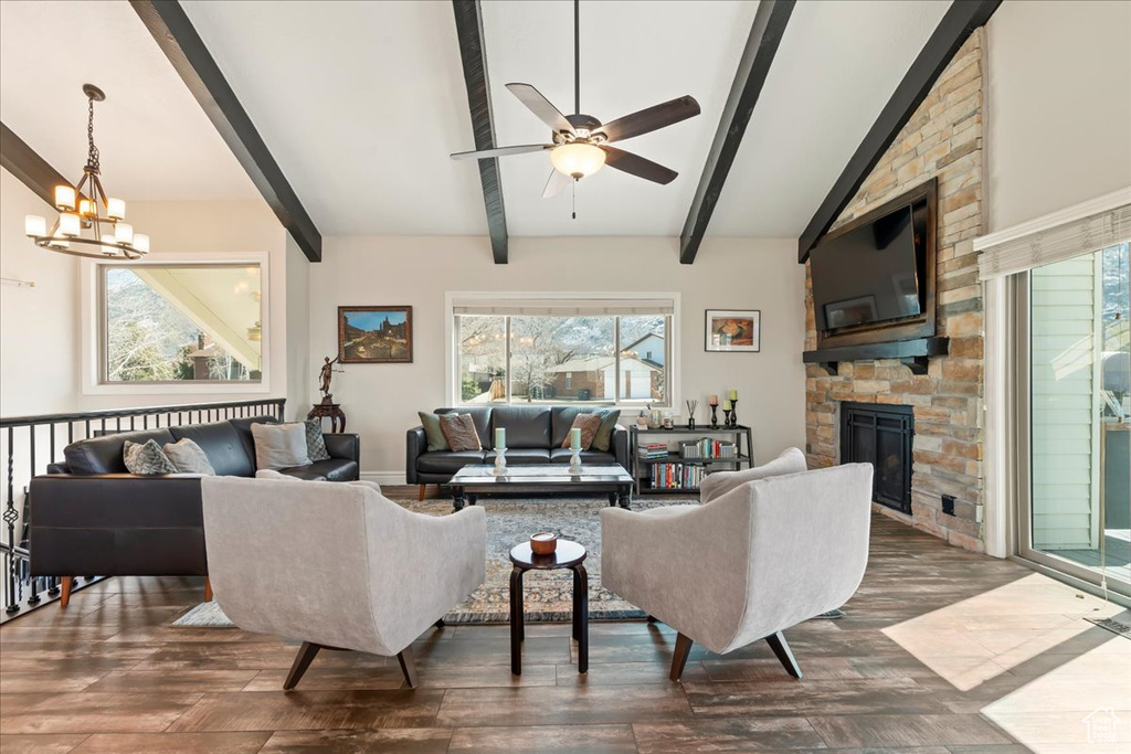 Living room featuring ceiling fan with notable chandelier, dark hardwood / wood-style flooring, a large fireplace, and a healthy amount of sunlight
