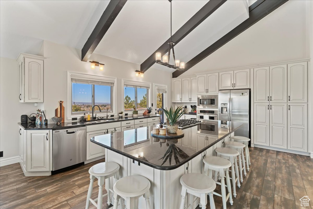 Kitchen featuring a center island, stainless steel appliances, beam ceiling, and a kitchen bar