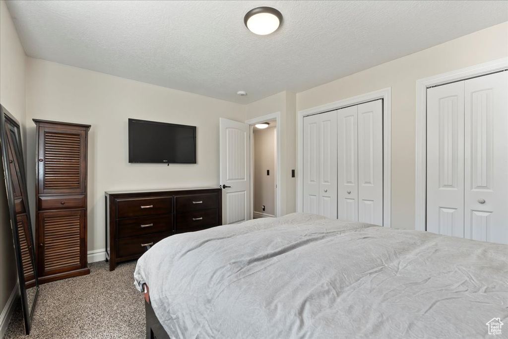 Bedroom with light carpet, a textured ceiling, and multiple closets