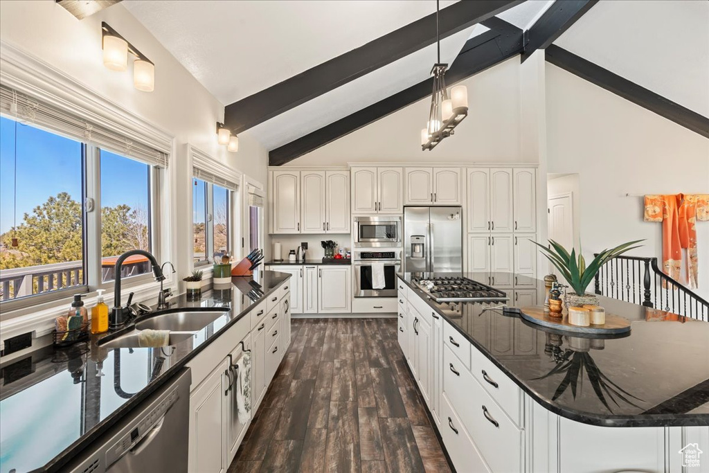 Kitchen featuring a kitchen island, dark hardwood / wood-style floors, appliances with stainless steel finishes, decorative light fixtures, and white cabinetry