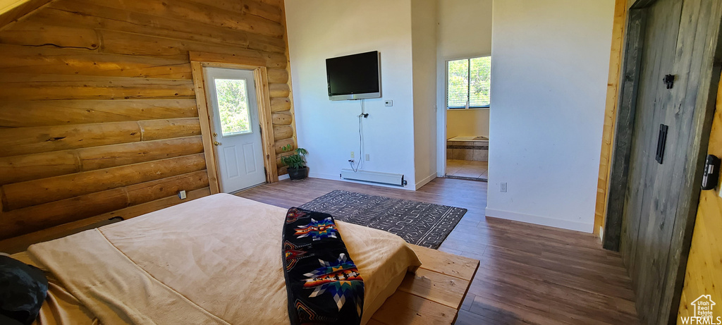 Bedroom featuring dark wood-type flooring, multiple windows, and log walls