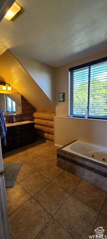 Bathroom with vanity, a textured ceiling, tile flooring, and a washtub