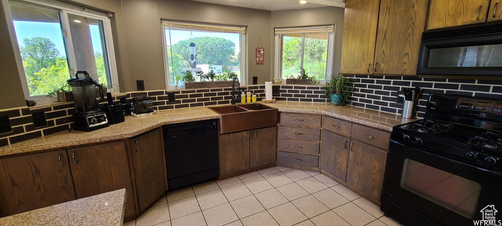 Kitchen featuring backsplash, light tile floors, and black appliances