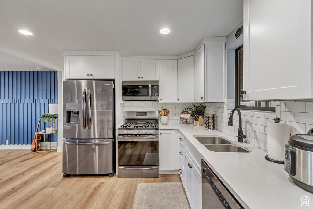 Kitchen featuring white cabinetry, appliances with stainless steel finishes, light hardwood / wood-style floors, and sink