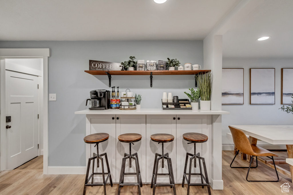 Kitchen featuring white cabinetry, light wood-type flooring, and a breakfast bar area