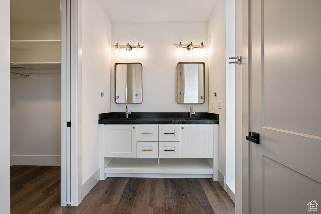 Bathroom featuring dual sinks, large vanity, and wood-type flooring