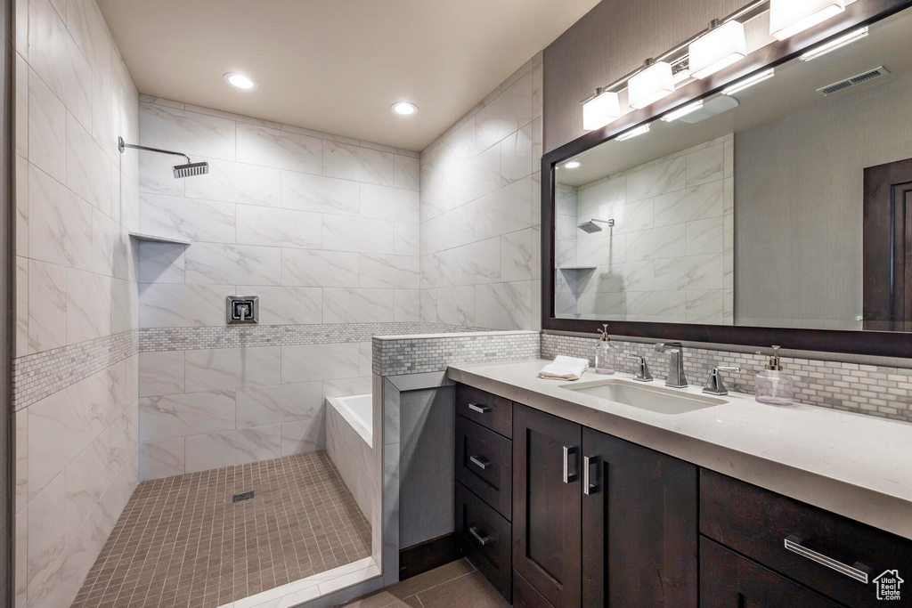 Bathroom featuring backsplash, vanity, independent shower and bath, and tile walls