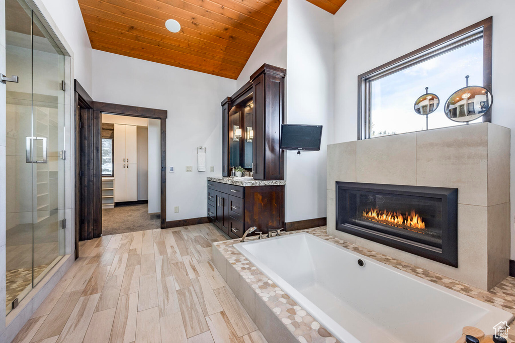 Bathroom with plenty of natural light, a tile fireplace, large vanity, and wood ceiling