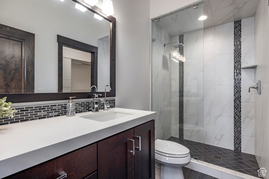 Bathroom with vanity, toilet, an enclosed shower, and backsplash