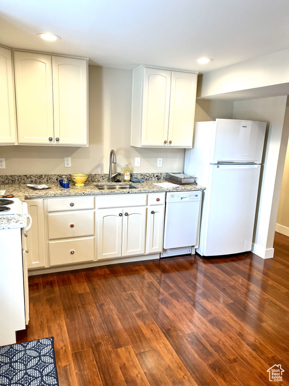 Kitchen with sink, white appliances, white cabinets, and dark wood-type flooring