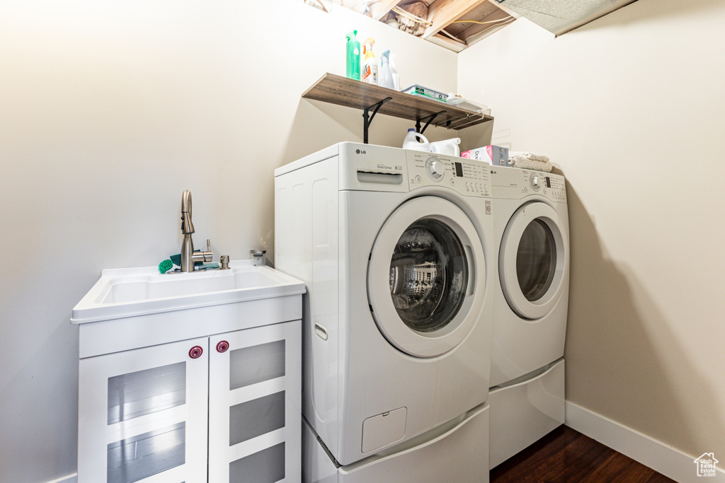 Clothes washing area with dark wood-type flooring, cabinets, and separate washer and dryer