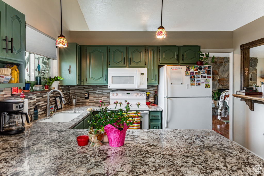 Kitchen featuring decorative light fixtures, white appliances, sink, and green cabinetry