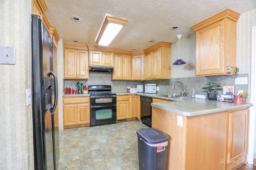 Kitchen with ventilation hood, black appliances, sink, light tile floors, and kitchen peninsula