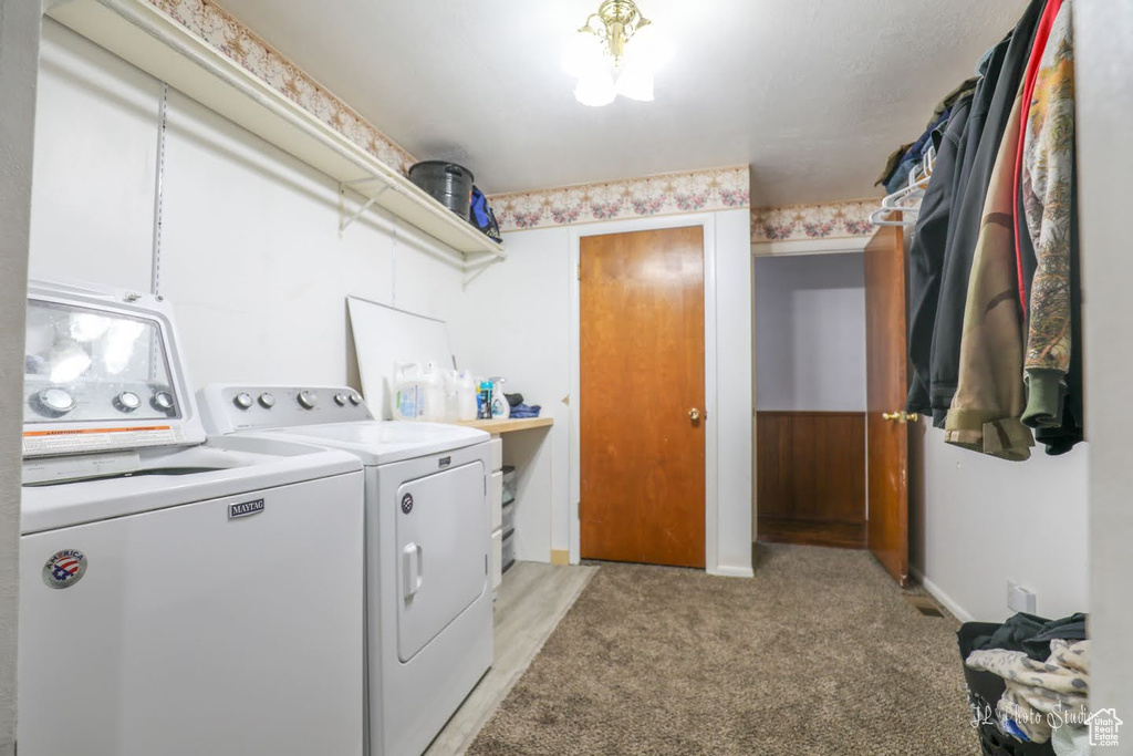 Clothes washing area with light colored carpet and washer and dryer