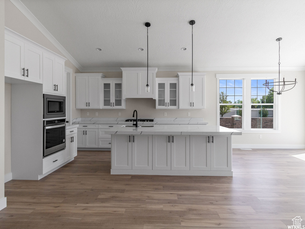 Kitchen featuring white cabinets, ornamental molding, pendant lighting, and stainless steel appliances