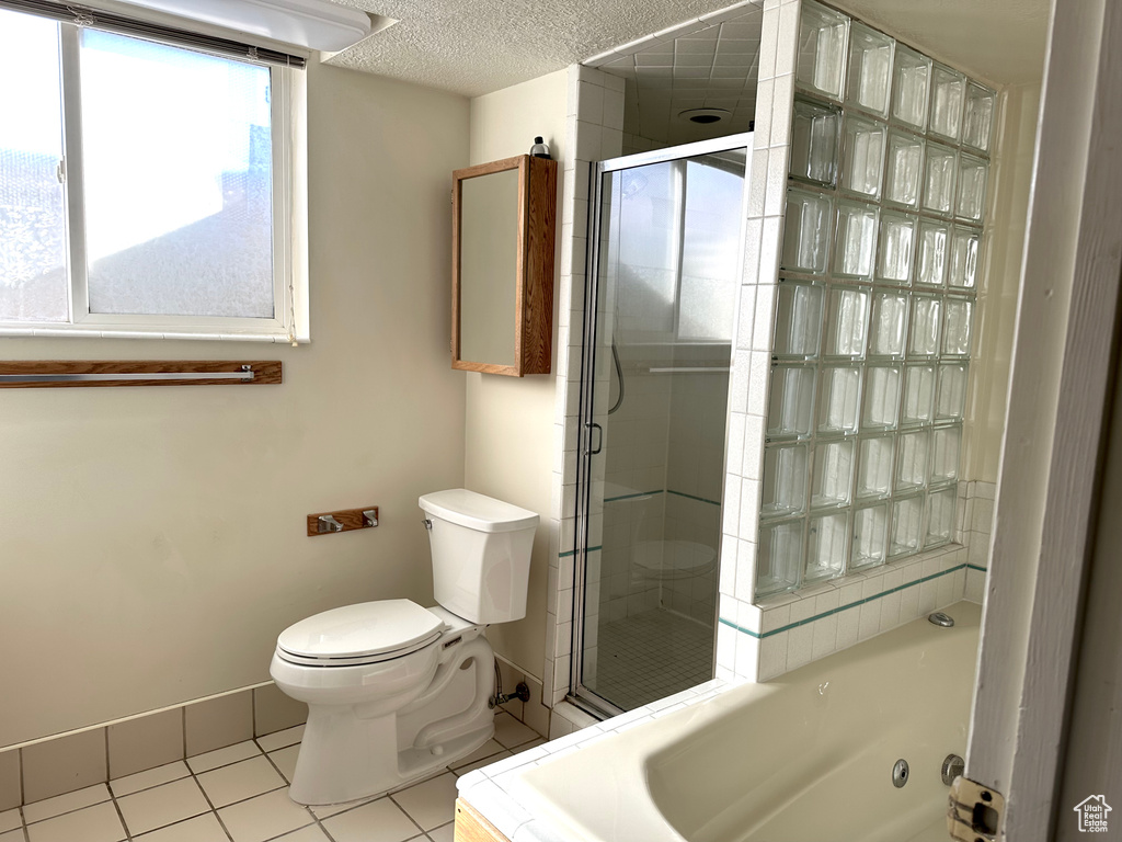 Bathroom with toilet, tile flooring, a textured ceiling, and a shower with shower door