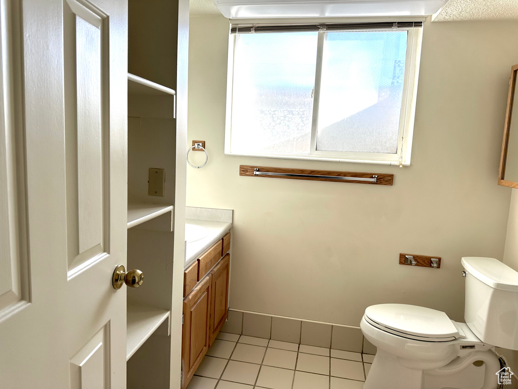 Bathroom featuring tile flooring, toilet, vanity, and a healthy amount of sunlight